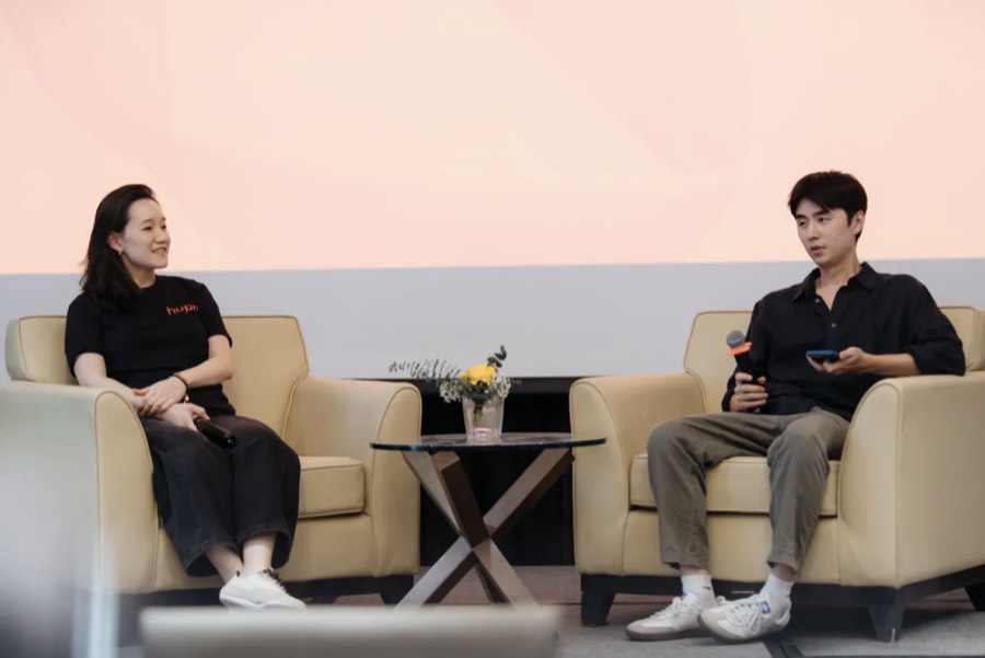 A Hupo team member interviewing a guest in armchairs on stage at a company event